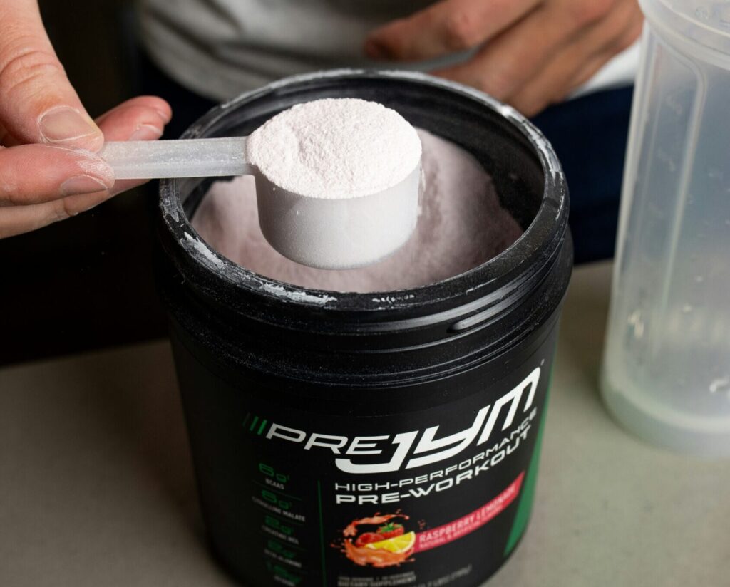 ボトルからスプーンですくったプロテインパウダー