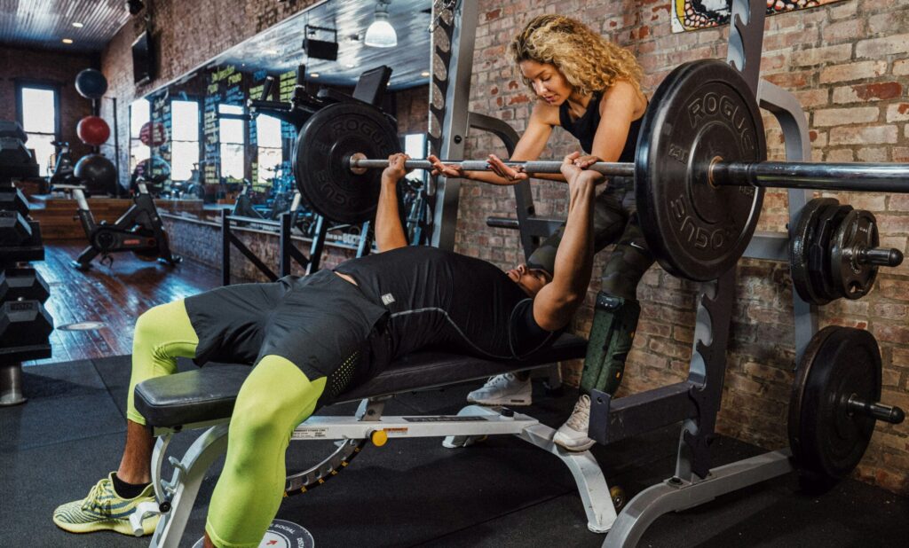 ベンチプレスをする男性とサポートする女性